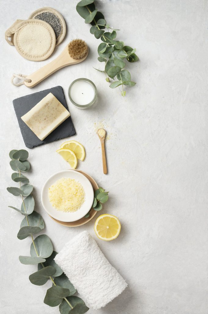 Flat lay organic yellow sea salt with lemon, soap, brush, sponge and eucalyptus branch