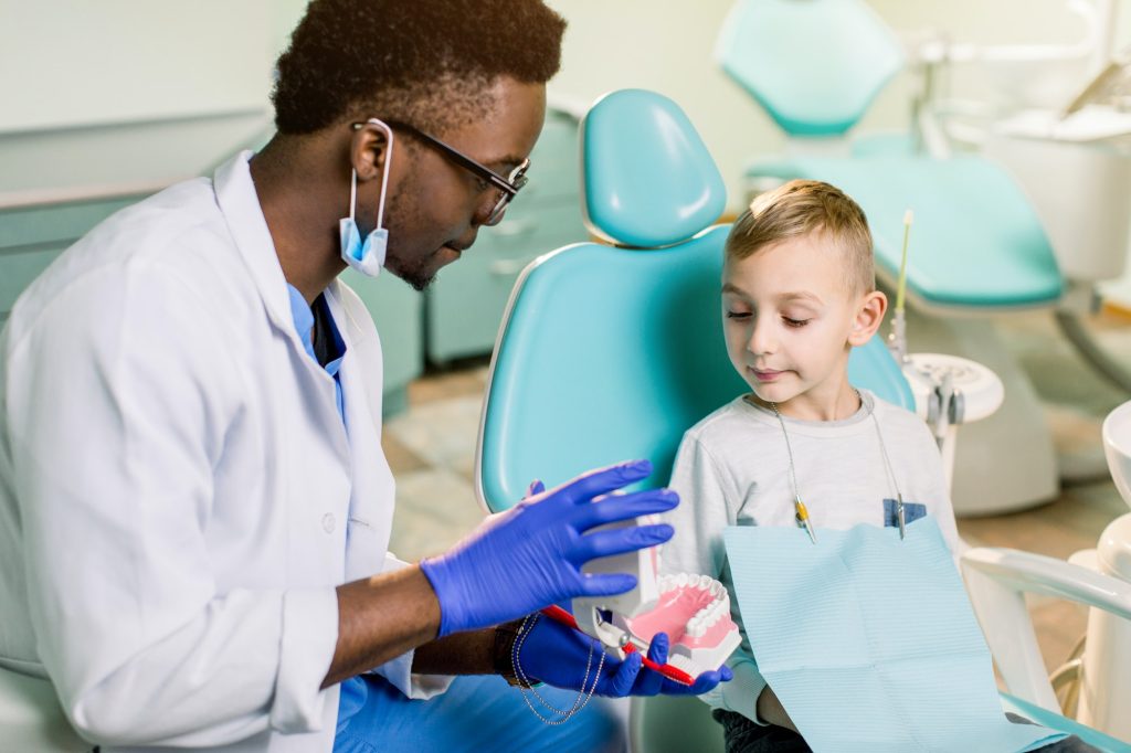 African American Man dentist in a uniform. Plastic jaw in the dentist's office.