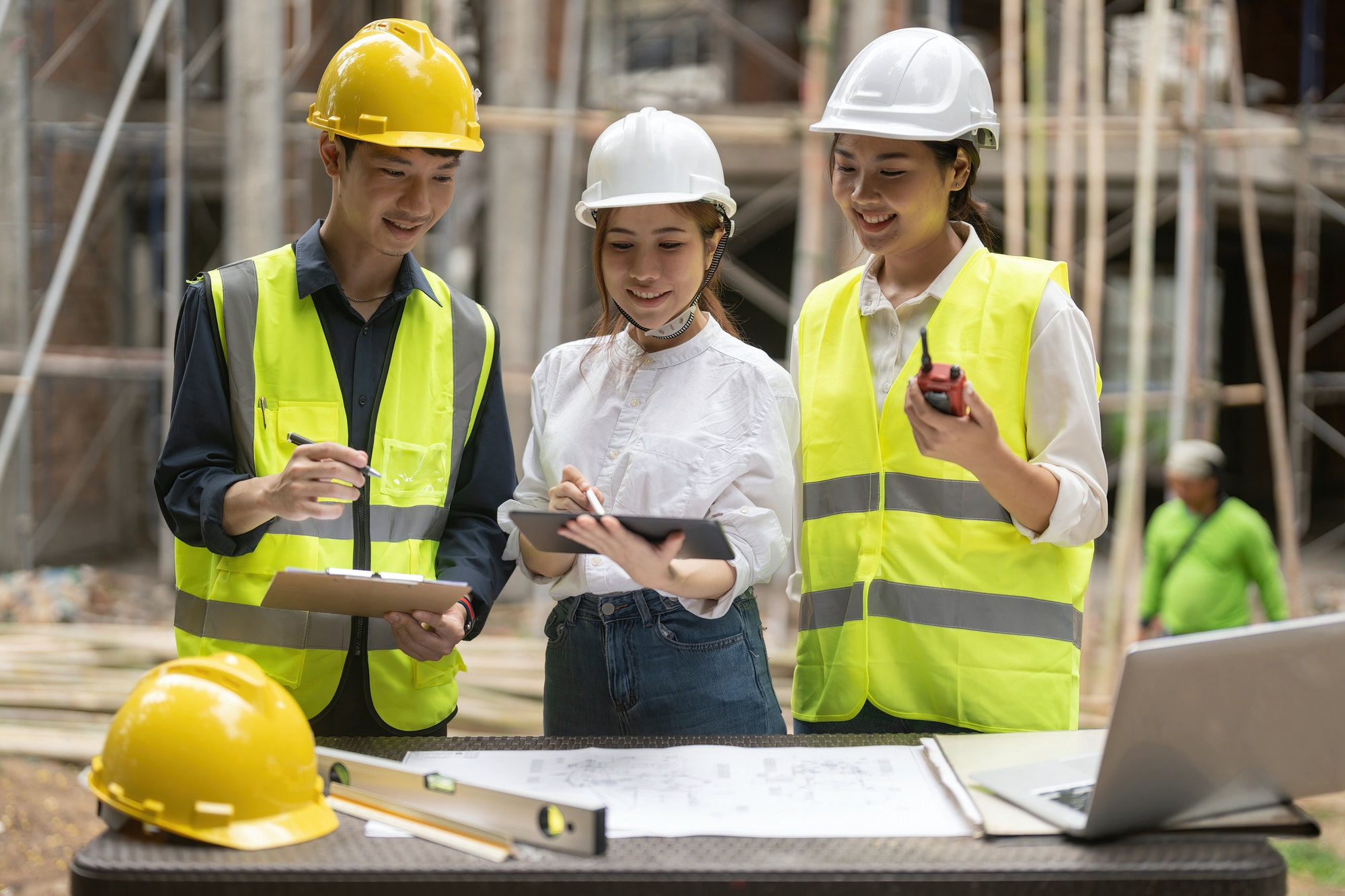 architector and engineers with draft plan of building and tablet computer talking on constructing