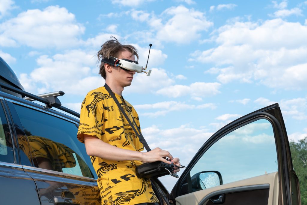 Caucasian guy man in observation glasses and a remote control for controlling a drone in his hands