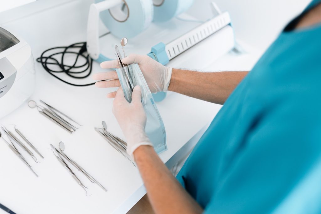 Dentist assistant sterilizing and packing dentist equipment