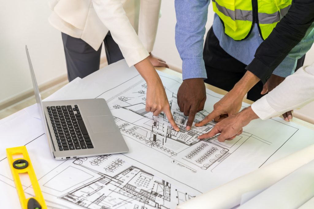 Engineers with draft plan of building on constructing site.