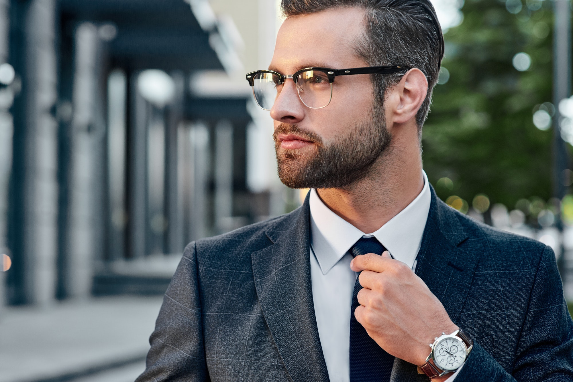 The young in spectacles men straightens his tie, his face unshaven